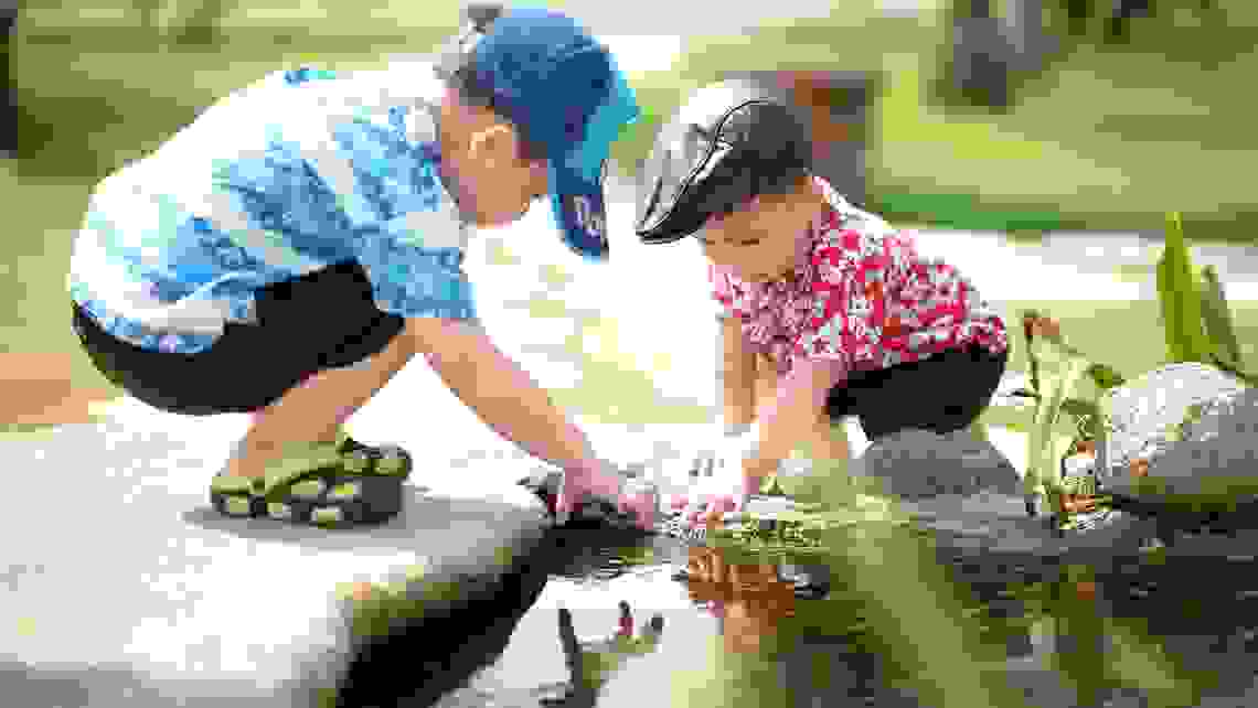 Två barn leker vid vatten. 