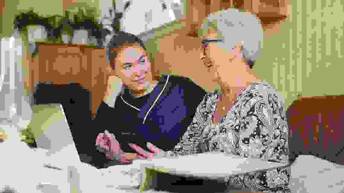 Hemtjänstpersonal hjälper äldre kvinna i hemmet