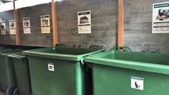 Stora gröna avfallskärl i ett återvinningsrum