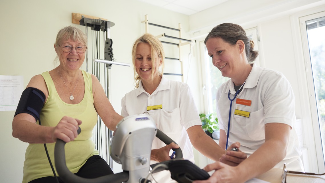 Patient på rehabilitering med fysioterapeut på motionscykel