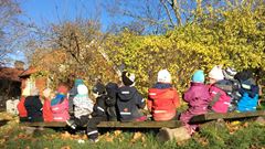 Barn sitter på en bänk utomhus under hösten. 