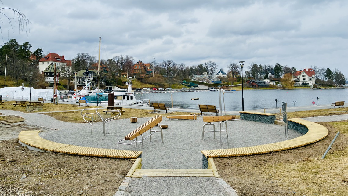 Ett utegym med vatten och båtar i bakgrunden.